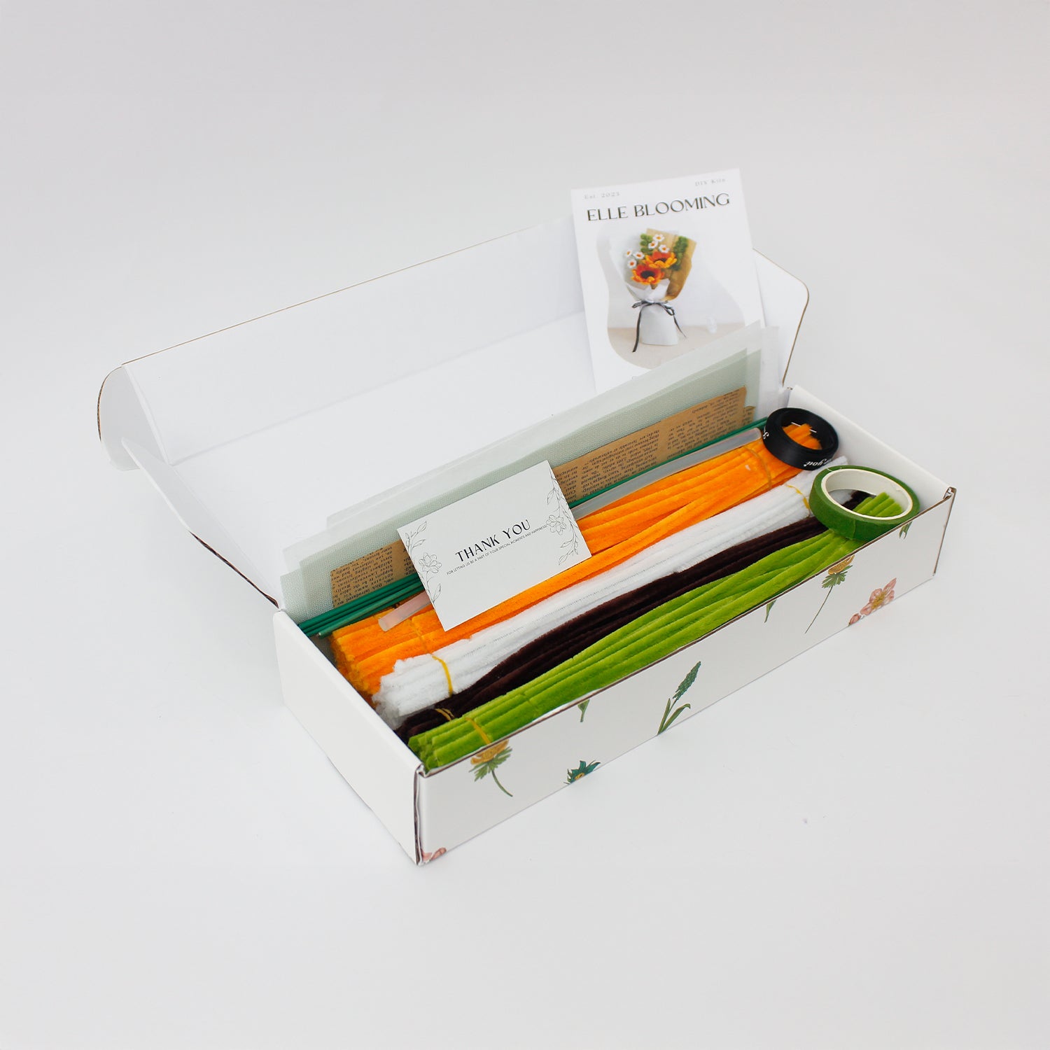 DIY bouquet of vibrant orange sunflowers and small white daisies made from fuzzy pipe cleaners. Wrapped in vintage-style kraft and pastel paper with a black ribbon perfect for handmade gift lovers.