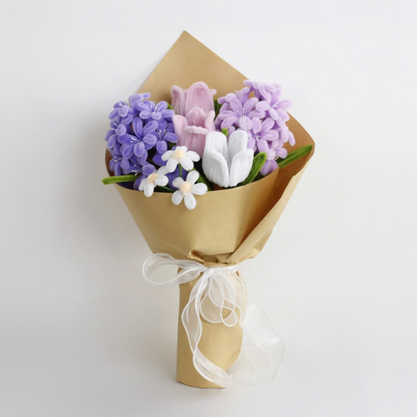 Bouquet of flowers wrapped in brown paper with a white ribbon on a light gray background