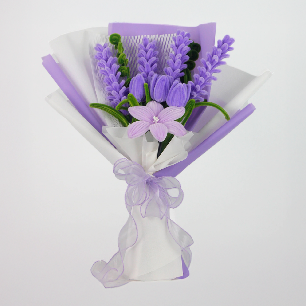 Bouquet of purple flowers wrapped in white paper with a purple ribbon on a light gray background