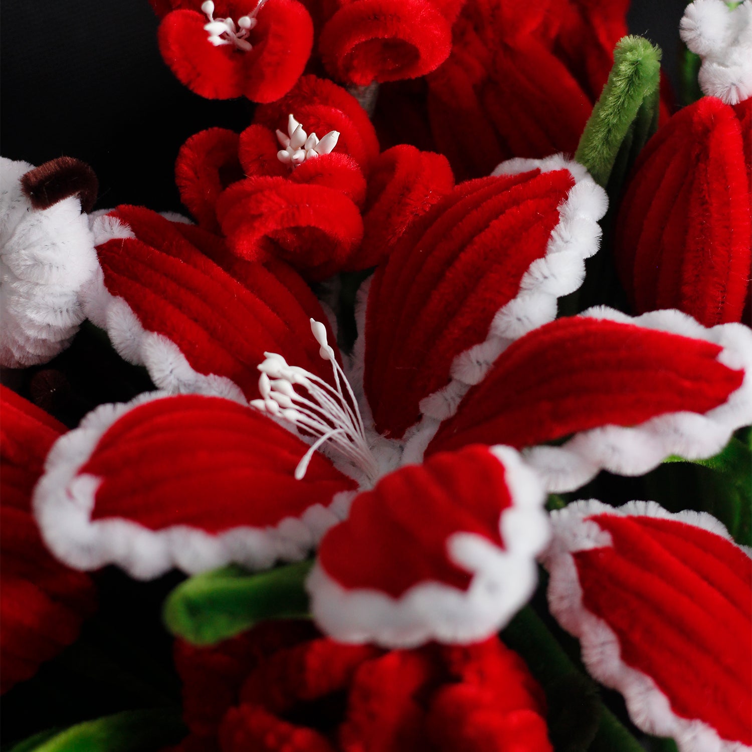 Red and white handmade pipe cleaner bouquet wrapped in festive Christmas paper with red bow. Features poinsettia-inspired flowers and snowflake accents. Ideal for holiday gifts.
