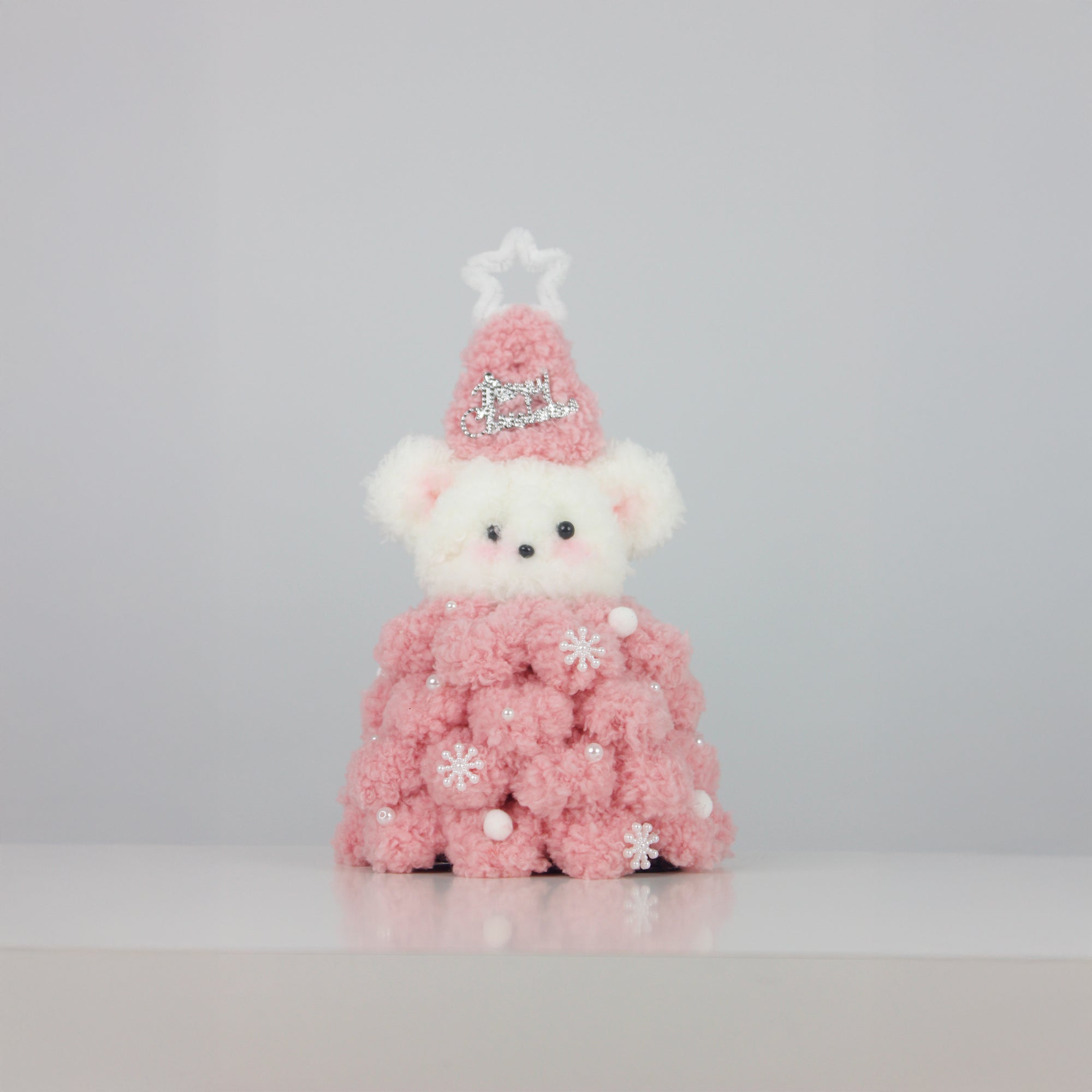 Soft pink Christmas bear wearing a fuzzy star hat and textured pipe cleaner dress with pearl snowflakes – a sweet DIY decor or gift for the holiday season.