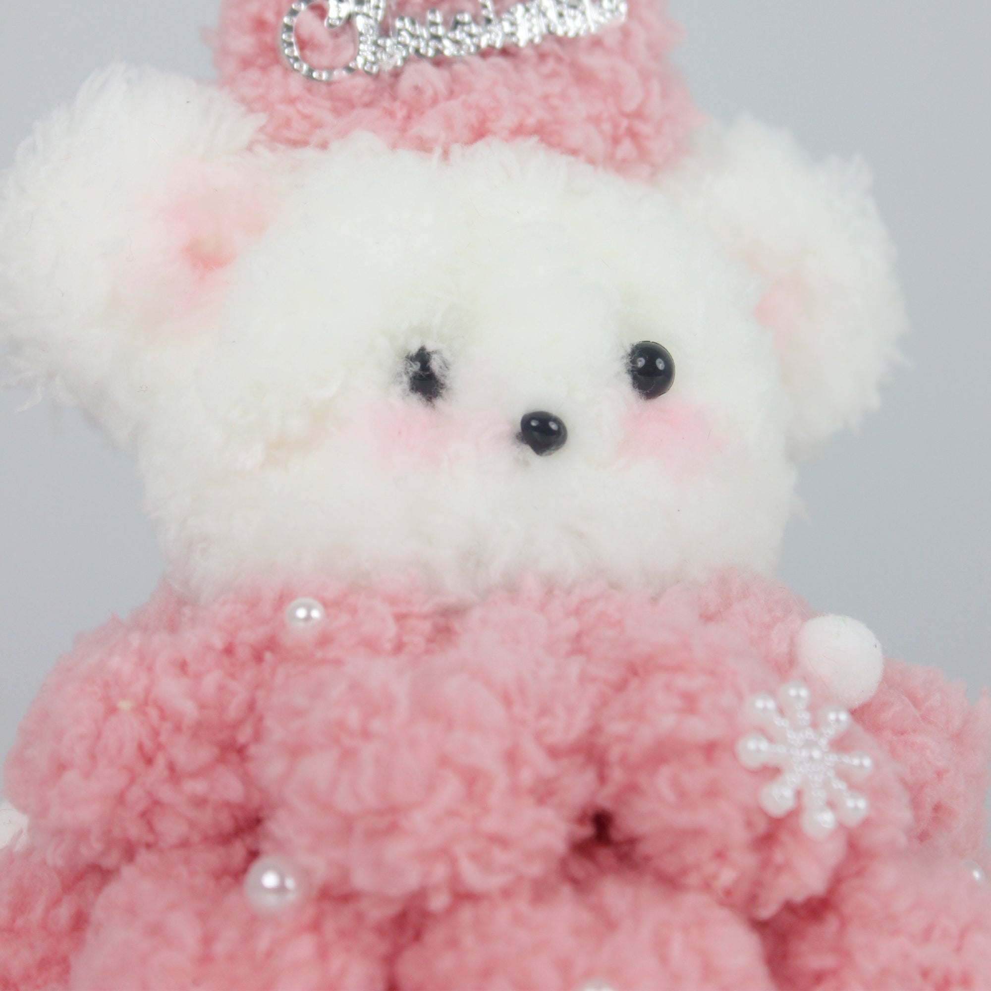 Soft pink Christmas bear wearing a fuzzy star hat and textured pipe cleaner dress with pearl snowflakes – a sweet DIY decor or gift for the holiday season.