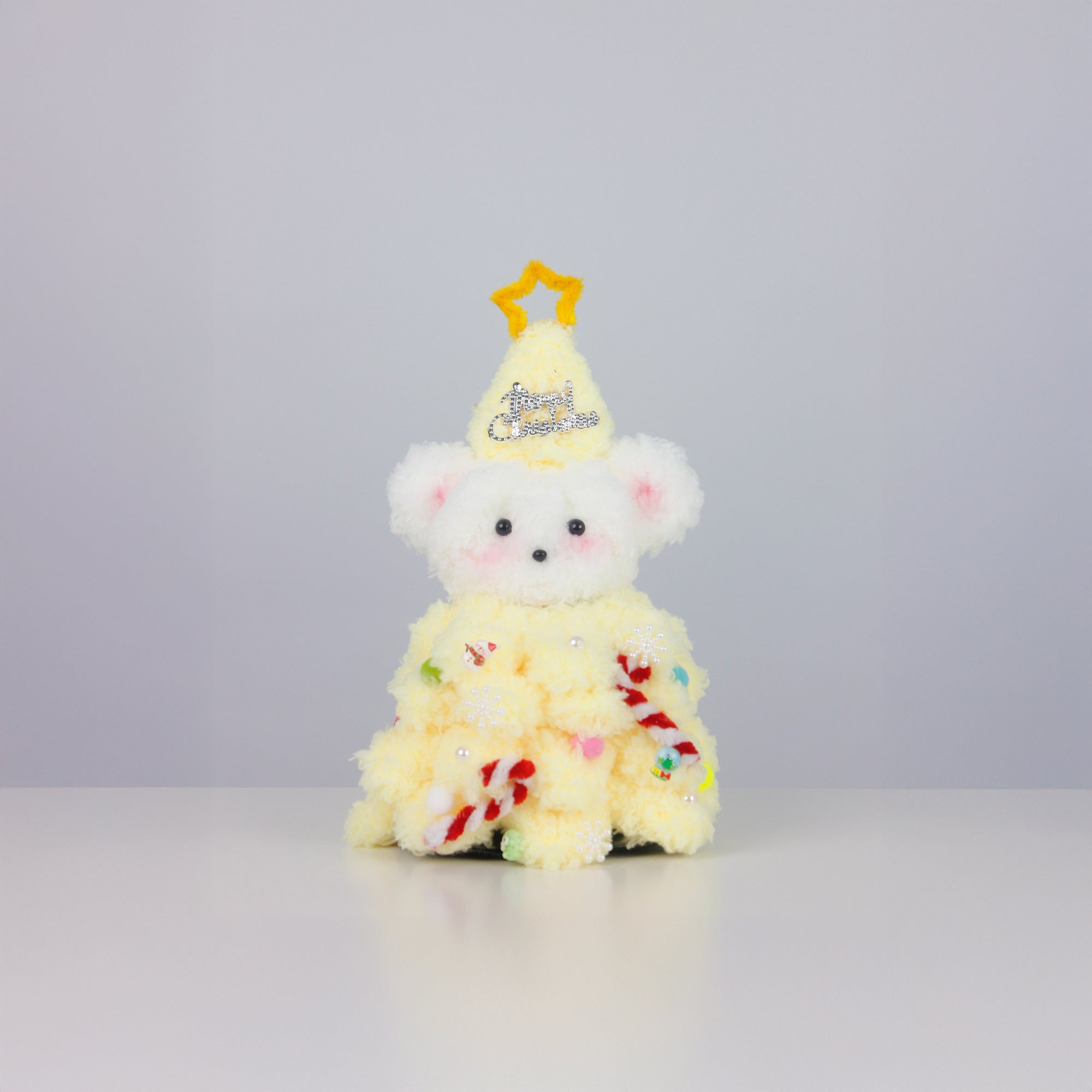 Fuzzy pipe cleaner bear dressed in a bright yellow Christmas tree dress with a star hat — creative handmade Christmas decoration.